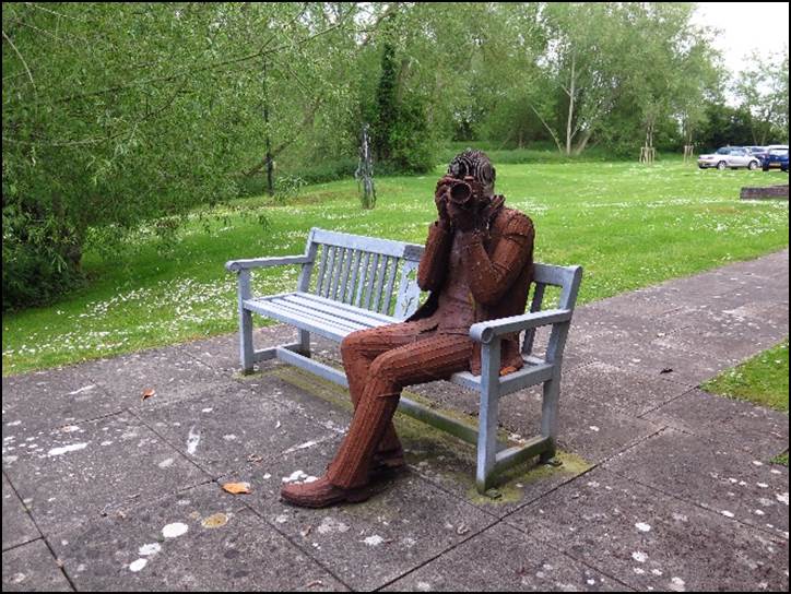 A statue of a person sitting on a bench

Description automatically generated