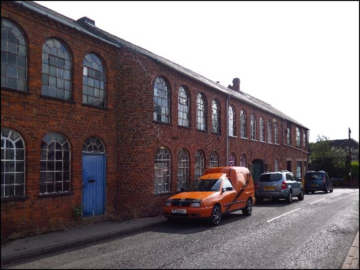 A car parked on the side of a road in front of a brick building

Description automatically generated with low confidence