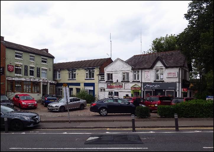 A street with cars parked on the side and buildings in the background

Description automatically generated with low confidence