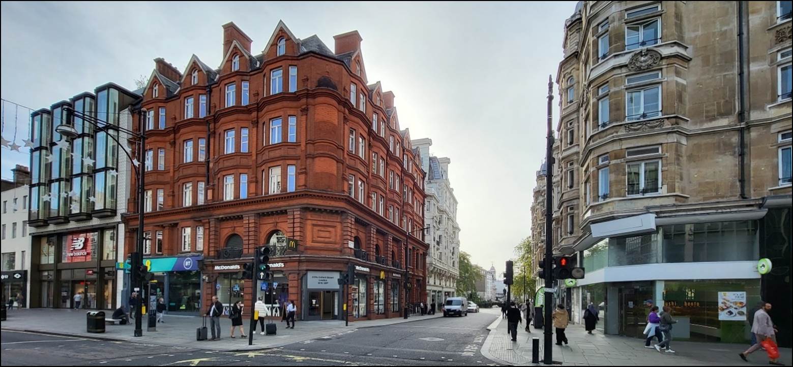 A street with a building and people walking on it

Description automatically generated