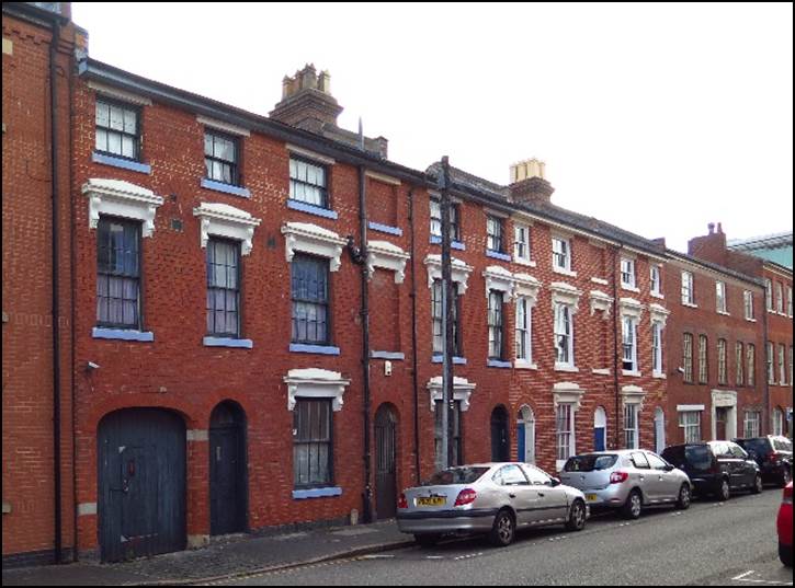 A street with cars parked on the side of a brick building

Description automatically generated