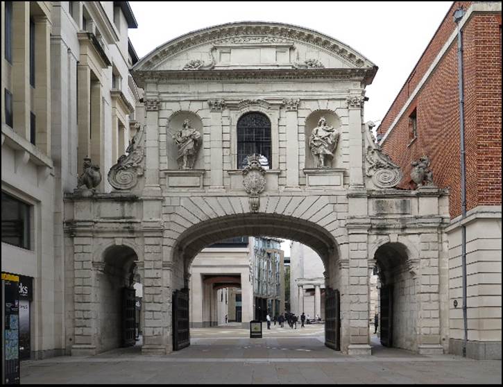 A stone archway with statues on the top

Description automatically generated