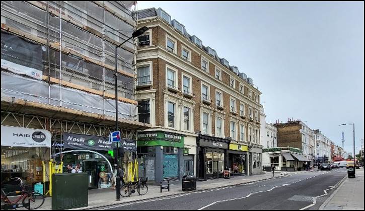 A street with a building and a bus stop

Description automatically generated