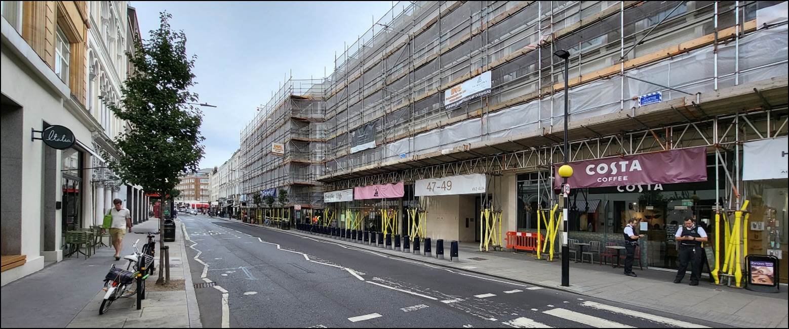 A street with a building and a parking lot

Description automatically generated