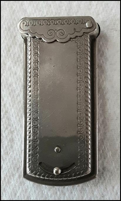 A silver rectangular object with a design

Description automatically generated