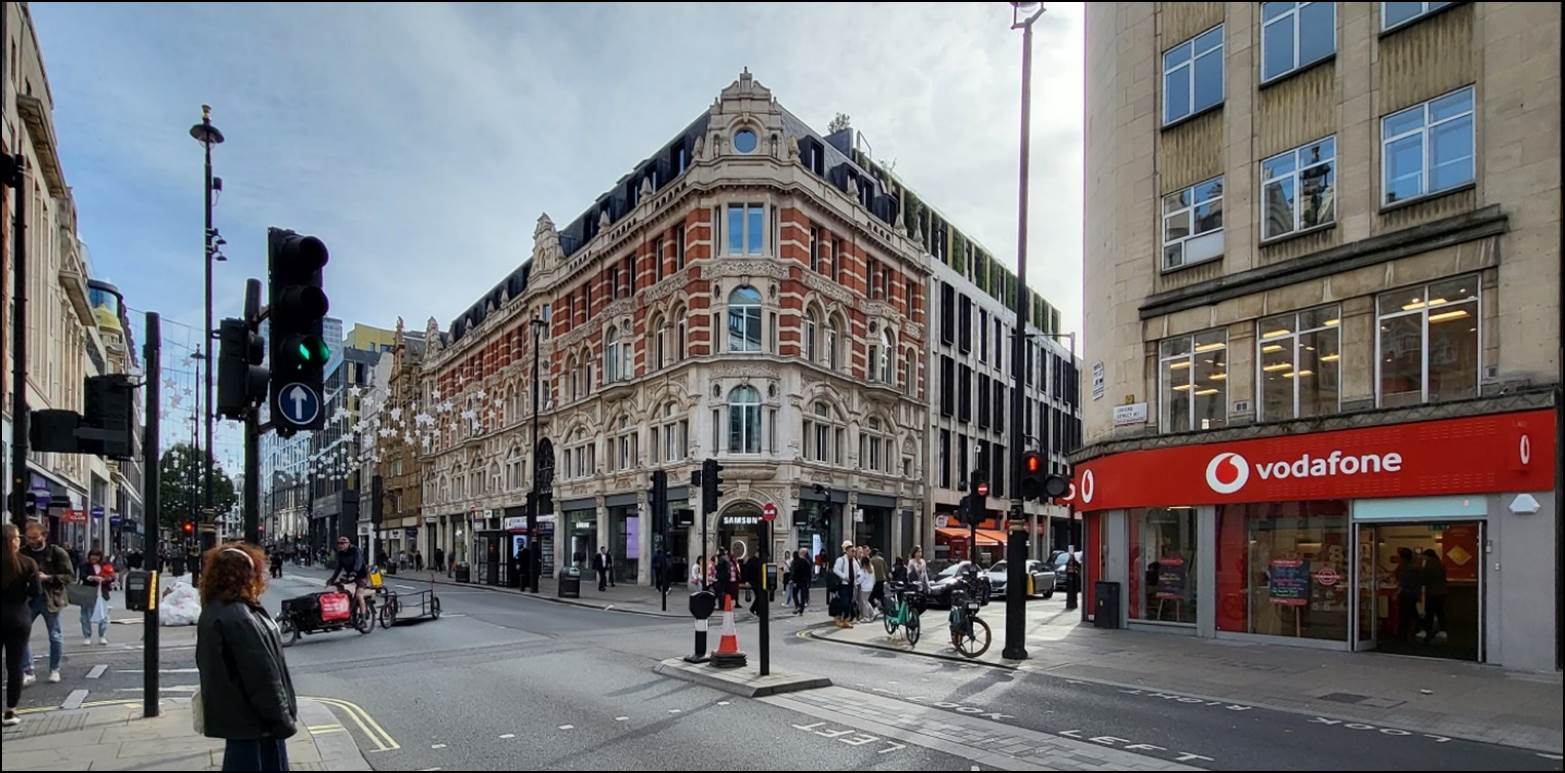 A street with a building and people walking on it

Description automatically generated