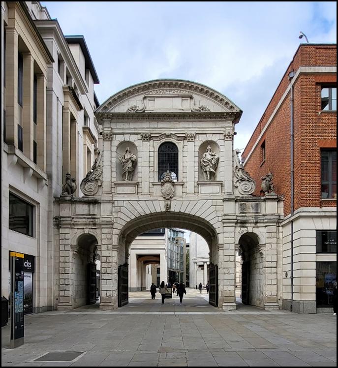 A stone archway with statues on the top

Description automatically generated