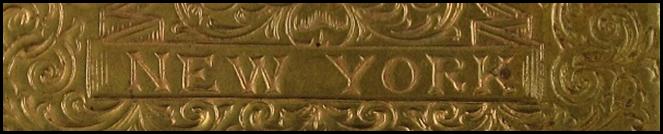 A gold square object with a symbol on it

Description automatically generated