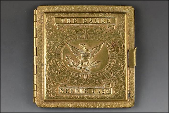A gold metal case with a eagle on it

Description automatically generated