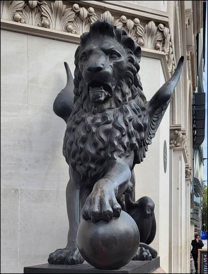 A statue of a lion with a ball

Description automatically generated