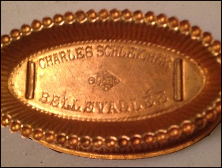 A gold oval object with writing on it

Description automatically generated