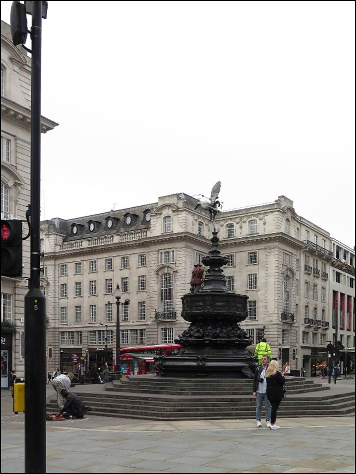A large building with a fountain in the middle with Buckingham Palace in the background

Description automatically generated
