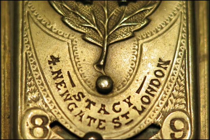 Close-up of a gold object with a leaf and numbers

Description automatically generated
