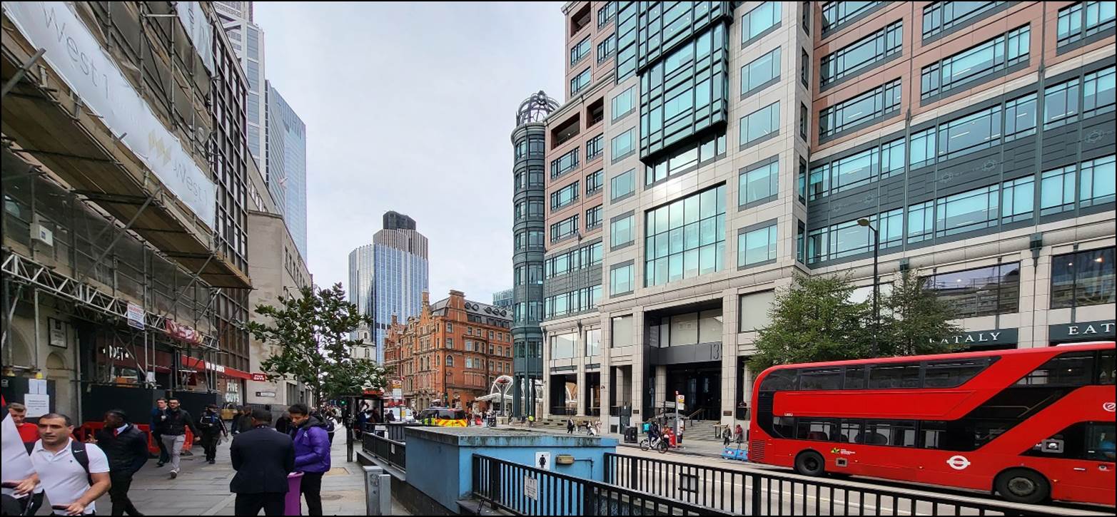 A group of people walking on a sidewalk in front of a building

Description automatically generated