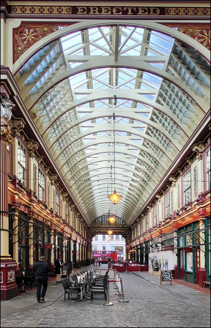 A large building with a glass roof with Leadenhall Market in the background

Description automatically generated