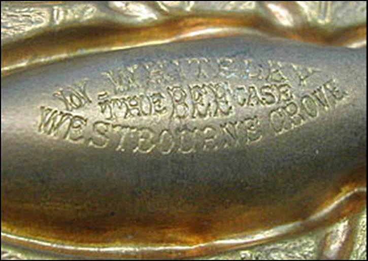 Close-up of a gold oval engraved on a metal surface

Description automatically generated