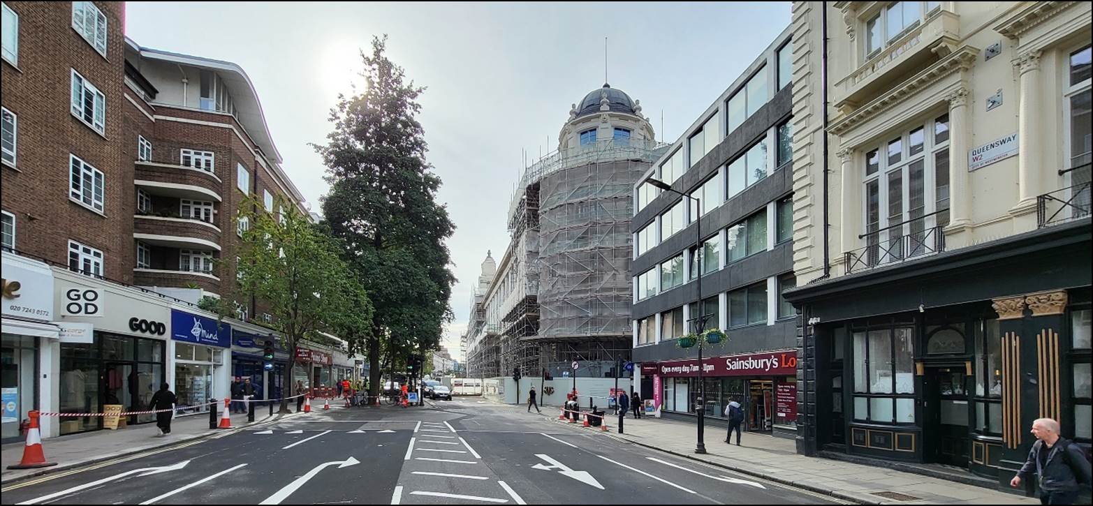 A street with buildings and people walking on it

Description automatically generated